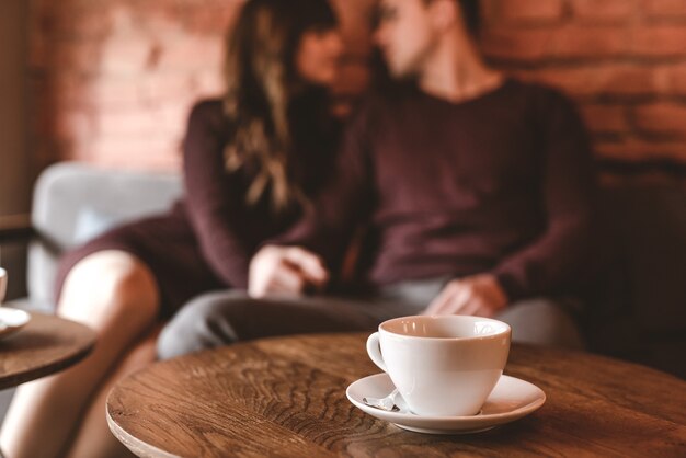 A xícara de café no fundo do casal sentado