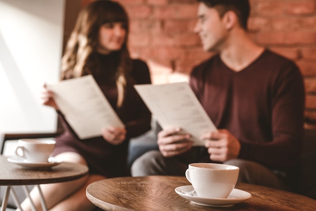 A xícara de café no fundo do casal sentado