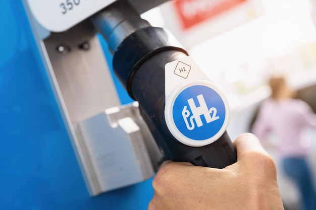 Aachen, Deutschland, Januar 2021: Frauen halten an Tankstelle eine Zapfsäule mit Wasserstoff. h2-Verbrennungsmotor für emissionsfreien, umweltfreundlichen Transport.