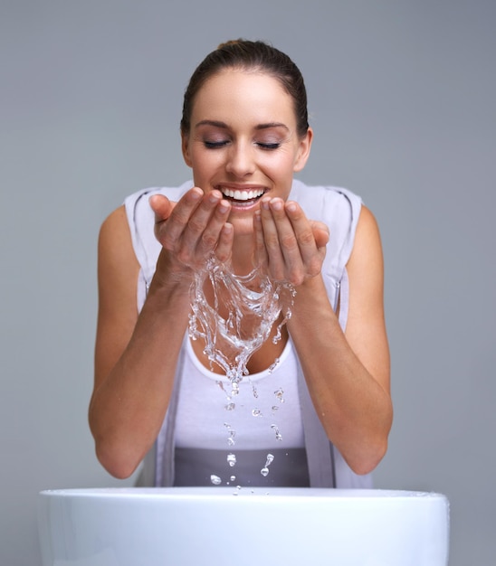 Foto aah tan refrescante una mujer joven y atractiva lavándose la cara