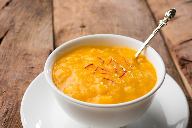 Aam Ras é uma deliciosa receita de sobremesa indiana sazonal, Aamras é puro Haapus ou Alphonso Mango Puree ou Polpa com Açafrão, cobertura kesar. Servido em uma tigela de terracota sobre fundo colorido.