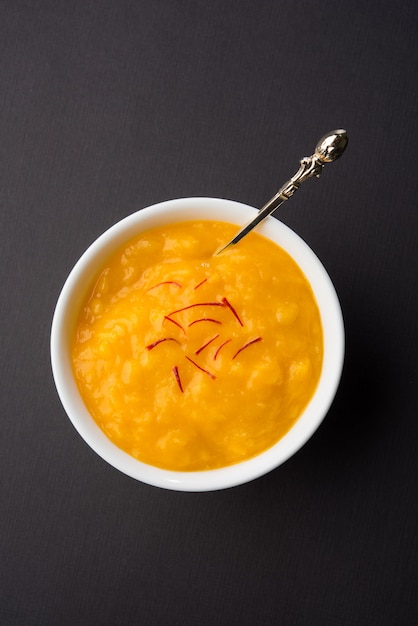 Aam Ras es una deliciosa receta de postre indio de temporada, Aamras es puro Haapus o Alphonso Mango Puré o Pulpa con azafrán, cobertura de kesar. Servido en un cuenco de terracota sobre fondo de colores.