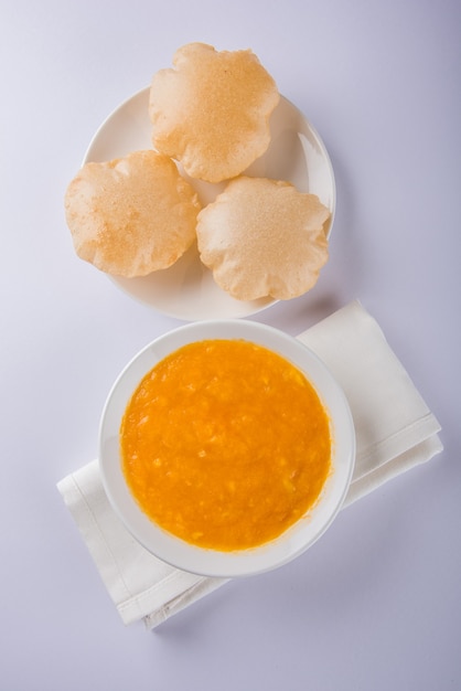 Aam Ras Puri es una deliciosa receta india que se sirve como postre de temporada, Aamras es puro puré o pulpa de mango, servido en un cuenco y plato de cerámica sobre un fondo colorido o de madera. Enfoque selectivo