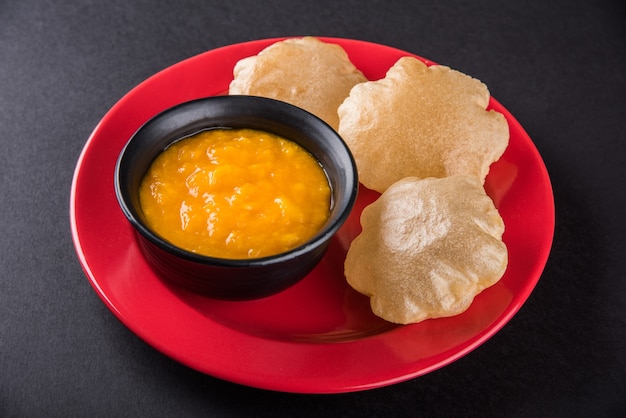 Aam Ras Puri ist ein köstliches indisches Rezept, das als saisonales Dessert serviert wird, Aamras ist einfaches Mango-Püree oder Fruchtfleisch, serviert in einer Keramikschale und einem Teller auf buntem oder hölzernem Hintergrund. Selektiver Fokus