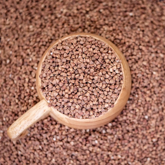 Aba de copo de madeira cheia de trigo sarraceno e cereais de fundo macio