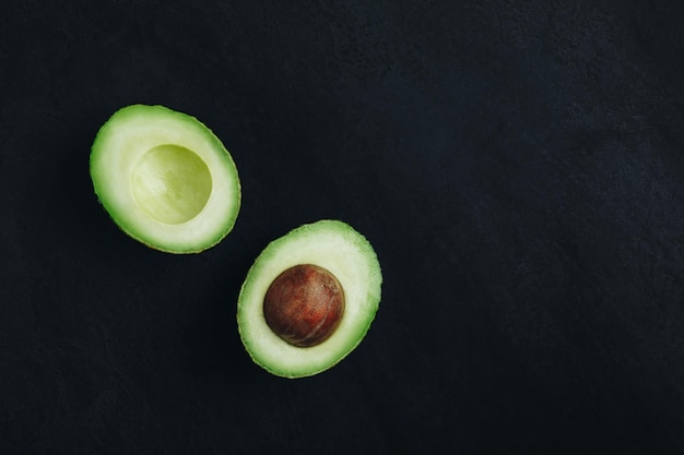 Abacate cru em fundo escuro de pedra Abacate maduro verde fresco para guacamole Espaço de cópia de vista superior