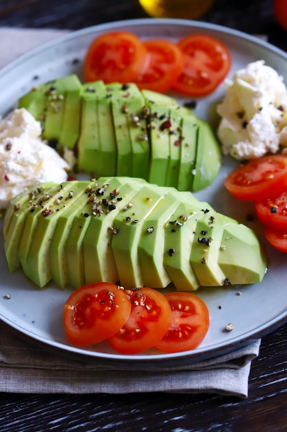 Abacate fatiado com cream cheese e tomate em um prato Macro de foco seletivo Dieta Keto