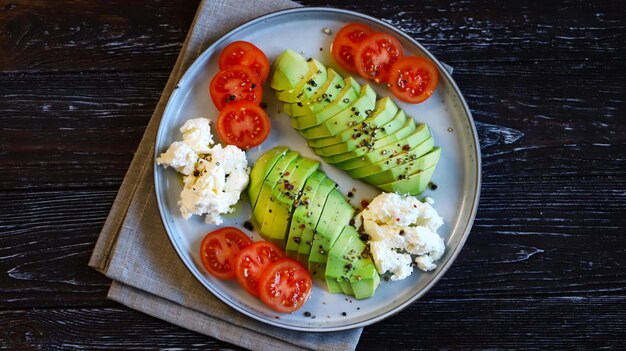 Abacate fatiado com cream cheese e tomate em um prato Macro de foco seletivo Dieta Keto