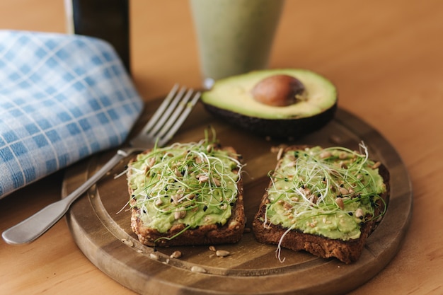 Foto abacate fresco e micro-verduras na torrada - o almoço ou lanche perfeito. servido com smoothie.