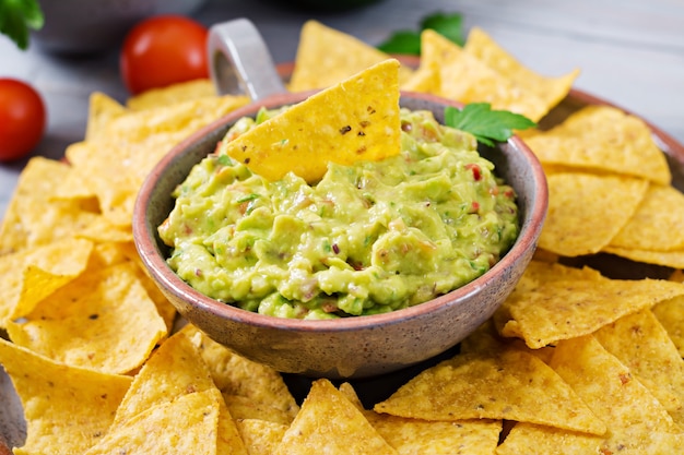 Abacate guacamole, limão, tomate, cebola e coentro, servido com nachos - lanche tradicional mexicano