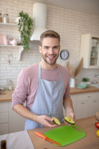 Abacate. Um homem sorridente cozinhando um novo prato com abacate