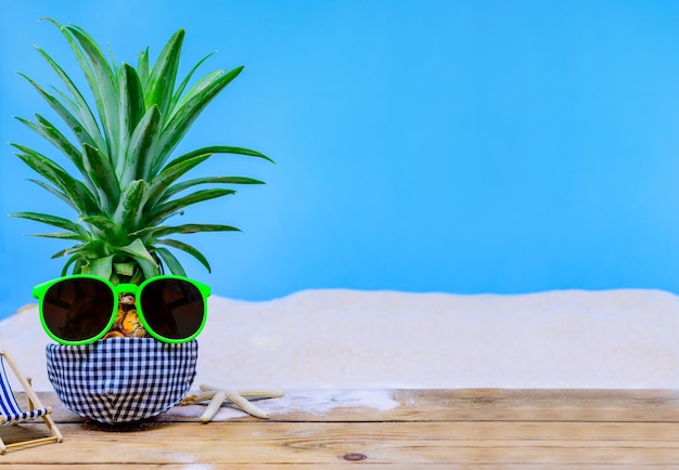 Abacaxi com óculos de sol em fundo de madeira. Conceito criativo mínimo de férias de verão