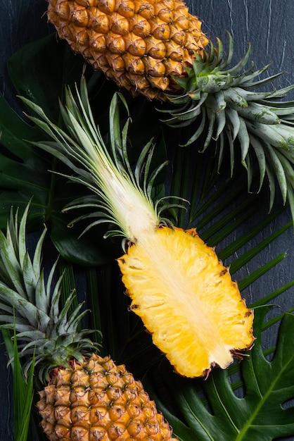 Abacaxi fresco cortado com folhas tropicais em fundo azul escuro