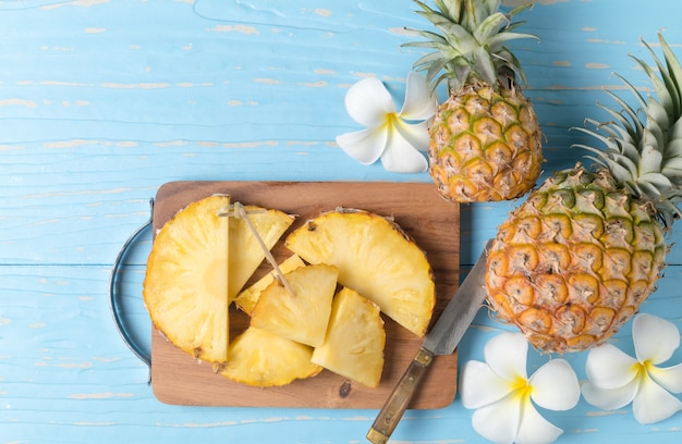 abacaxi fresco fatiado em bloco de madeira e fundo de madeira azul, conceito de frutas de verão