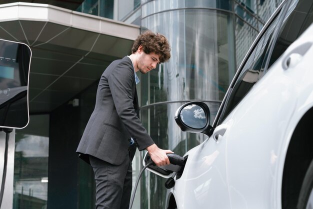 Abaixo, veja o empresário de terno preto progressivo recarregando a bateria do carro EV