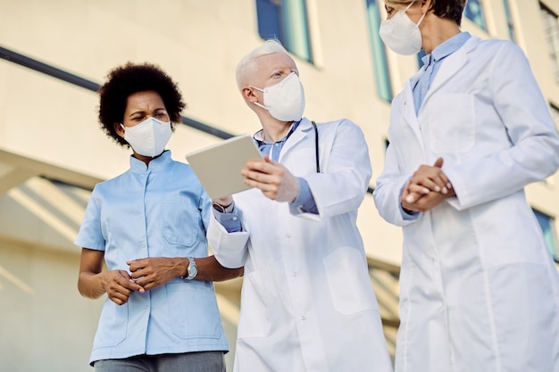 Foto abaixo vista da equipe de médicos usando o touchpad enquanto fala ao ar livre