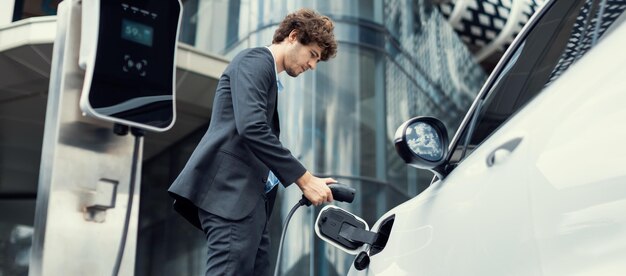 Abajo ver primer plano progresivo traje negro empresario recargar la batería del coche EV