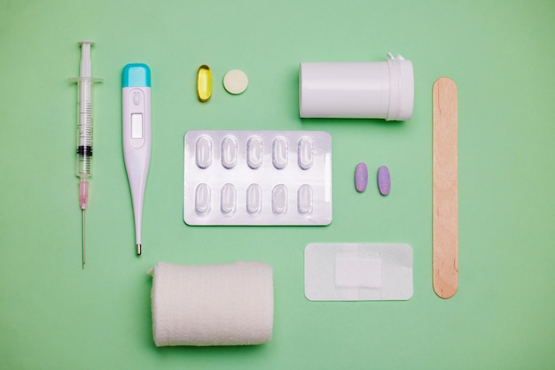 Abastecimento de cuidados de saúde medicamentos e ferramentas médicas em estúdio para bem-estar de saúde ou kit de primeiros socorros em fundo verde Termômetro vazio e bandagem para injeção de seringa Equipamento médico ou superior