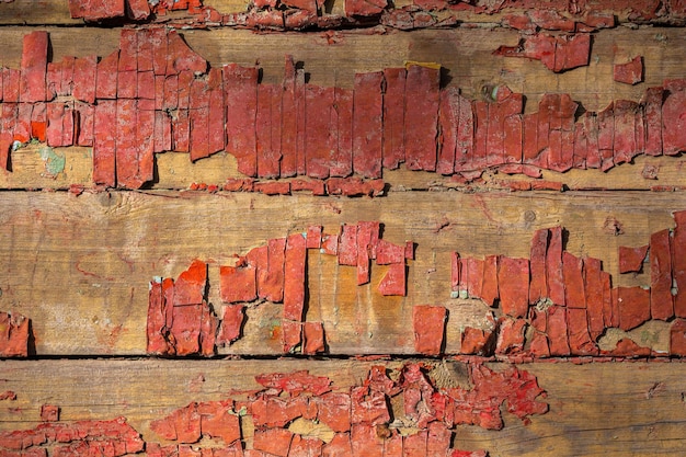 Abblätternde verblasste rote Farbe auf horizontalen Holzbohlen