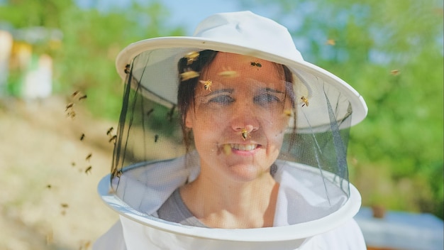 Abejas volando alrededor de la cara de un apicultor