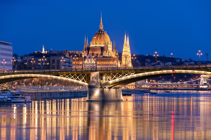 Foto abend in budapest, parlament vor dem hintergrund der margaretenbrücke, die reflexion der lichter im wasser