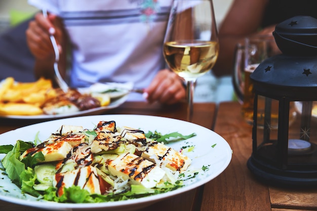 Foto abendessen im restaurant. nahaufnahmesalat mit gegrilltem käse. menschen essen im hintergrund