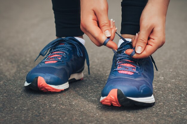 Abendlauf. Junge Dame, die auf einer Landstraße während des Sonnenuntergangs in den blauen Turnschuhen läuft