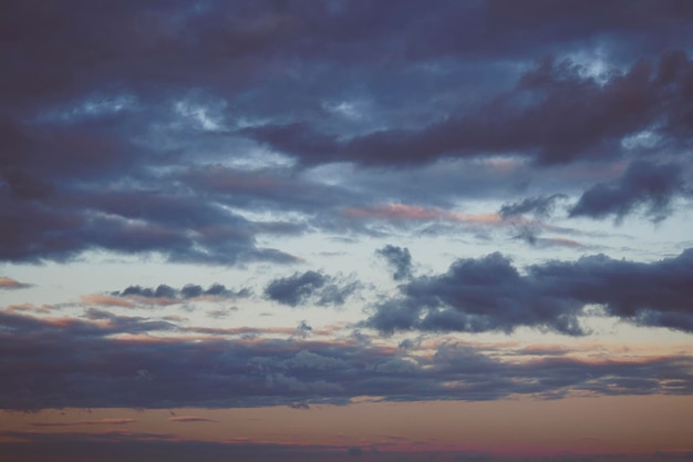 Abendliche Himmelsszene mit goldenem Licht von der untergehenden Sonne und Blaufärbung gefüllt mit Wolkenstreifen auf dunkelblauem Hintergrund