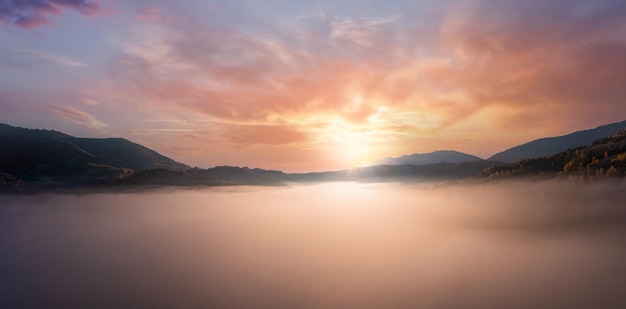 Abendlicht zwischen Wolken über bergiger Schlucht im Nebel