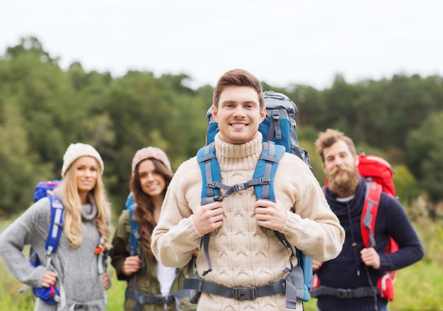 abenteuer, reise, tourismus, wanderung und personenkonzept - gruppe lächelnder freunde, die mit rucksäcken stehen