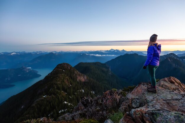 Abenteuerlustige Frau auf einer Bergklippe genießt den Sommersonnenaufgang