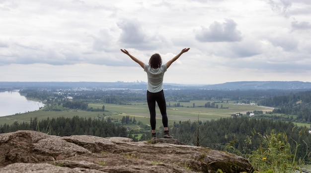 Foto abenteuerlustige frau, die auf einem felsen steht und die kanadische naturlandschaft überblickt