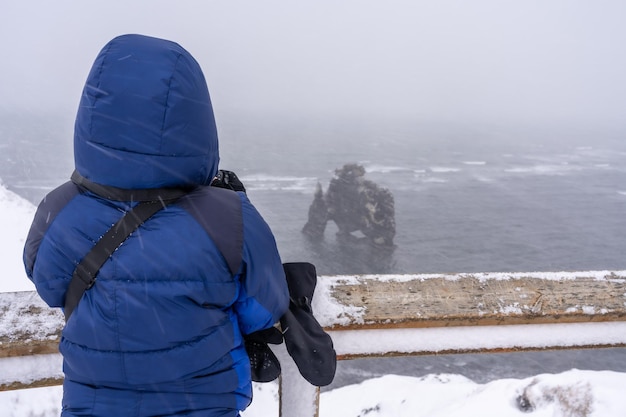 Abenteuerlustige Frau im Winter in Island, die die gefrorene Figur von Hvitserkur betrachtet