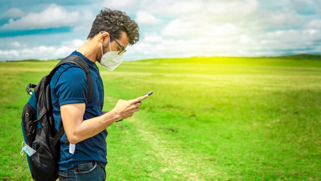 Abenteuerlustiger Mann im Feld mit Telefon Mann mit Rucksack im Chat im Feld