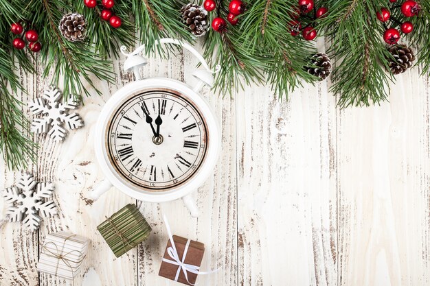 Abeto con adornos navideños, reloj despertador y cajas de regalo sobre fondo de madera rústica