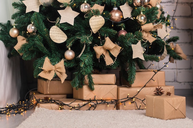 Abeto artificial navideño decorado con juguetes y regalos de guirnaldas debajo del árbol