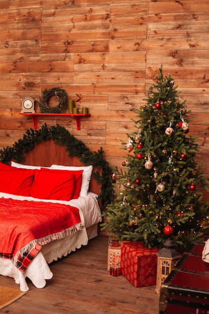 Abeto de natal e a cama. interior de ano novo do quarto com cama e árvore de natal.