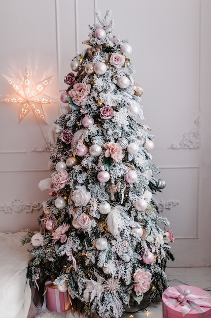 Abeto decorado con guirnaldas, cajas de regalos en una habitación blanca