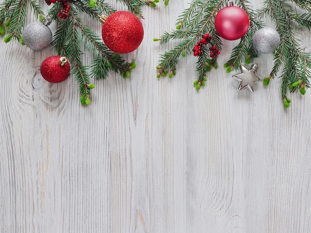 Abeto de Navidad, bolas rojas y plateadas y estrellas, bayas en mesa de madera.