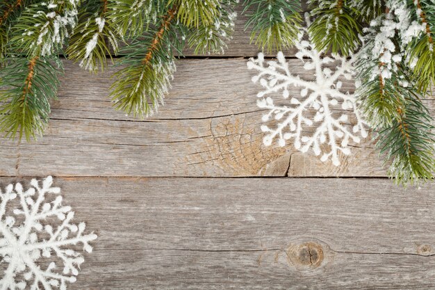 Abeto de Navidad y decoración cubiertos de nieve sobre fondo de tablero de madera
