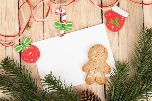 Foto abeto de navidad, galletas de jengibre y tarjeta para copiar el espacio en la mesa de madera