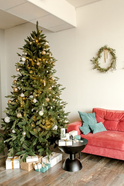 Abeto de Navidad en el interior de Año Nuevo decorado con guirnaldas y bolas de juguetes verdes de oro rojo