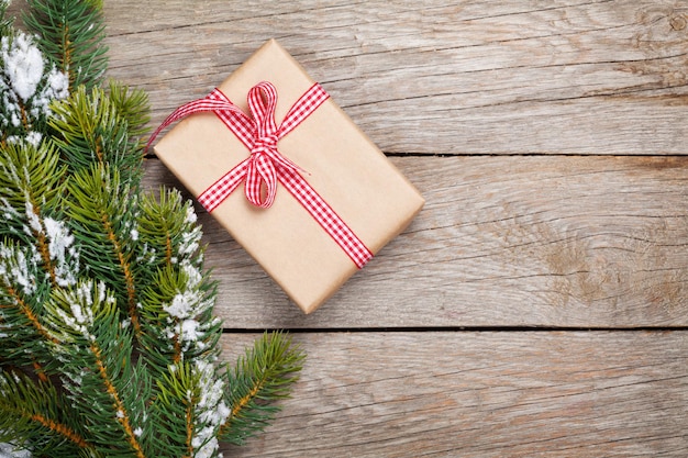 Abeto de navidad con nieve y caja de regalo.