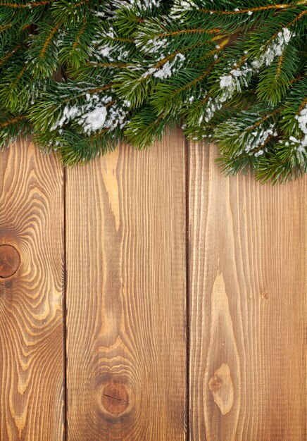 Abeto de navidad con nieve en tablero de madera rústico