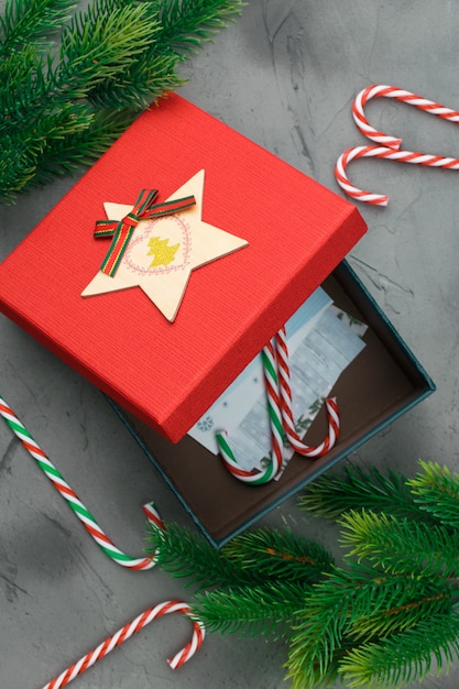 Foto el abeto ramifica en fondo gris concreto con la caja de regalo roja. espacio para texto plano.