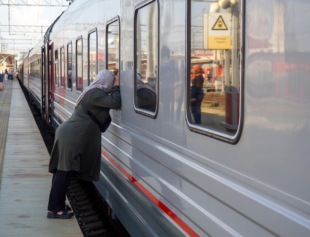 Abfahrt des Zuges Abschied einer Frau mit Kopftuch am Bahnhof