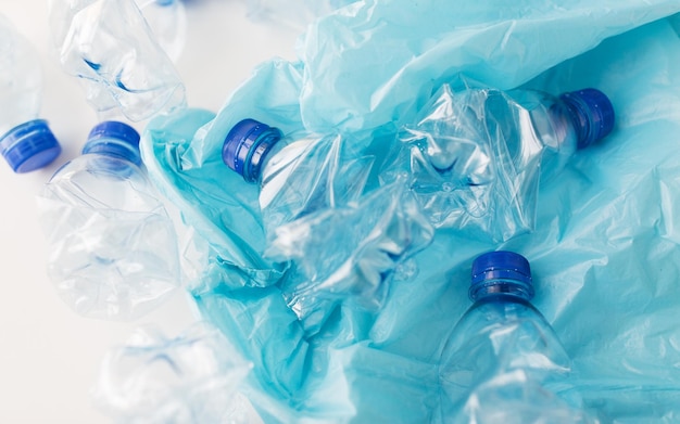 abfallrecycling, wiederverwendung, müllentsorgung, umwelt- und ökologiekonzept - nahaufnahme leerer gebrauchter plastikwasserflaschen und müllbeutel auf dem tisch