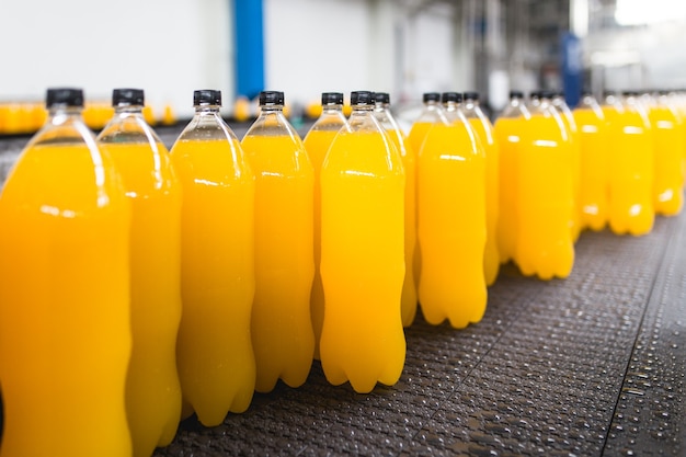 Abfüllfabrik - Orangensaft-Abfülllinie zur Verarbeitung und Abfüllung von Saft in Flaschen. Selektiver Fokus.