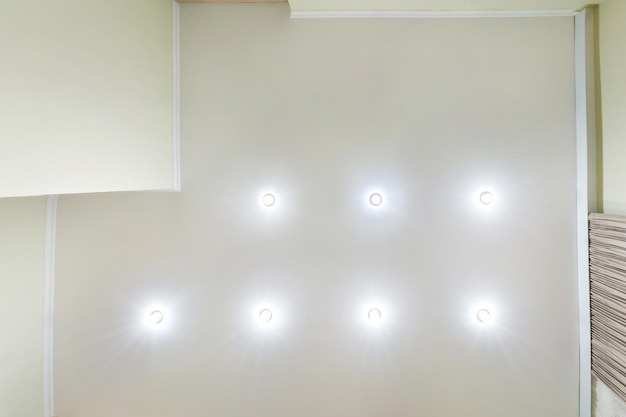 Abgehängte Decke mit LED-Lichtspot-Lampen und Trockenbau in leerem Raum in Wohnung oder Haus Spanndecke weiß und komplexe Form nach oben