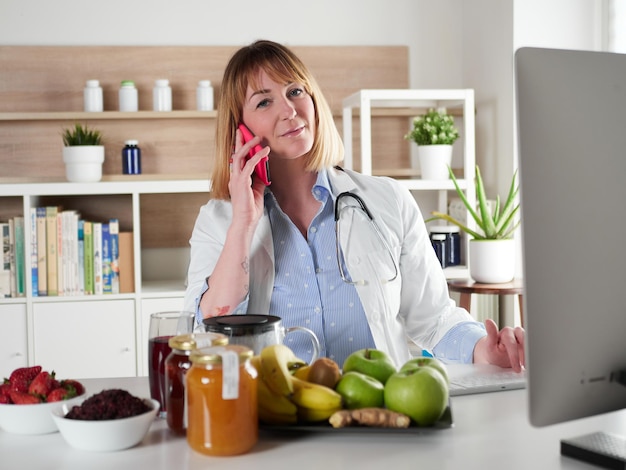 Foto abgelenkte ernährungsberaterin chattet mit smartphone im bürostudio